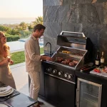 zwei Männer und eine lachende Frau stehen an der Outdoorküche Liverpool und grillen