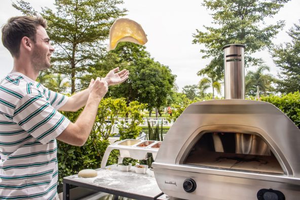 Junger Mann formt den Pizzateig