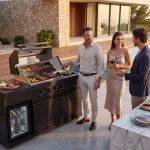 zwei Männer und eine Frau grillen und unterhalten sich an der Outdoorküche Dublin